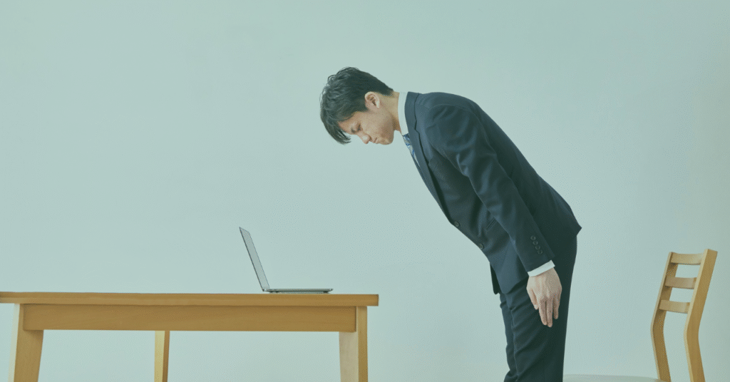 パソコンの前でお辞儀をしている人の画像